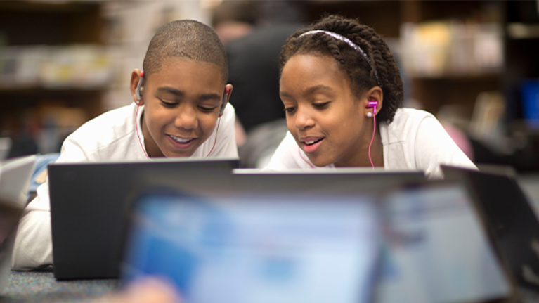 Two children work at a laptop